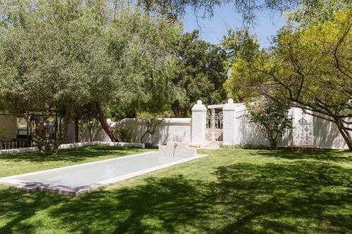 a garden with a white fence and trees at De Bergkant in Prince Albert