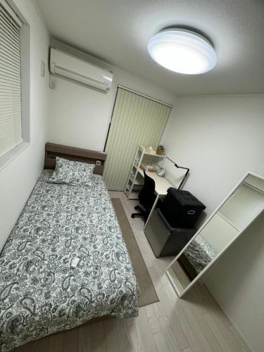 a small bedroom with a bed and a desk at Kenzo House in Kawasaki