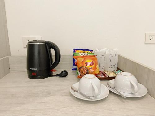 a kitchen counter with a coffee pot and cups and snacks at GRAND PA Hotel&Resort Lamphun Chiang Mai in Lamphun