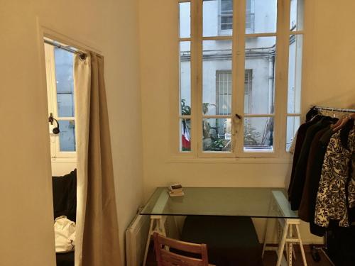Cette chambre dispose d'une table en verre et d'une fenêtre. dans l'établissement Une nuit au calme à Bastille, à Paris