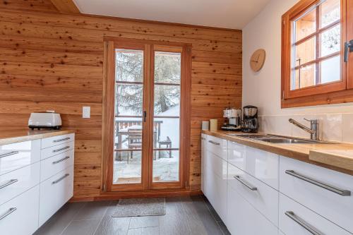 a kitchen with white cabinets and wooden walls at Croix Noires FABULOUS & LUXURY chalet 11 pers by Alpvision Résidences in Vex