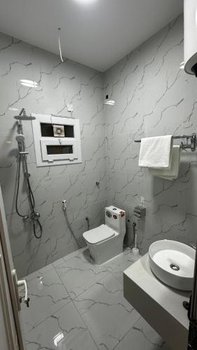 a white bathroom with a toilet and a sink at Wadi Front Apartment 2 in Nizwa