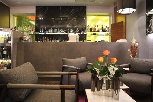 a bar with chairs and flowers on a table at Zepter Hotel Belgrade, member of Zepter Hotels in Belgrade