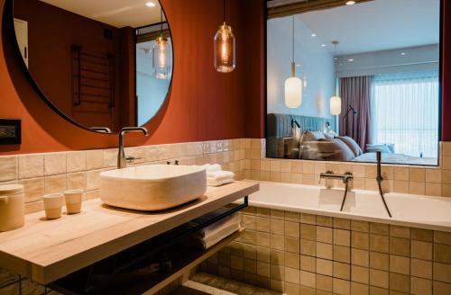 a bathroom with a sink and a tub and a mirror at A-ROSA Gardasee in Salò