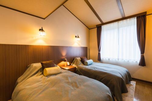a bedroom with two beds and a window at Hotel Jogakura in Aomori