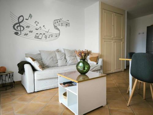 a living room with a couch and a vase on a table at Appartement T2 magnifique vue sur golf avec climatisation avec piscine in Saumane-de-Vaucluse