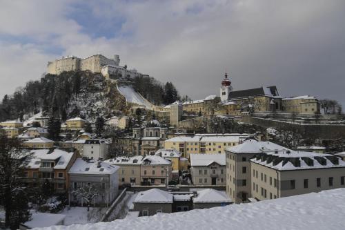 a snow covered city with a castle on a mountain at JUFA Hotel Salzburg in Salzburg