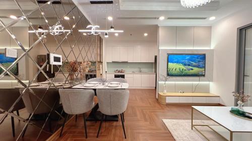 a kitchen with a dining table with chairs and a tv at KABILUX HOUSE - 1-2-3 Bedrooms in Vinhomes Times City in Hanoi