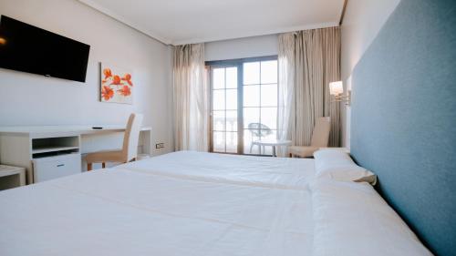 a bedroom with a large white bed and a desk at Hotel Bahia Sur in San Fernando