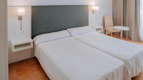 a bedroom with a large white bed with a green headboard at Hotel Bahia Sur in San Fernando