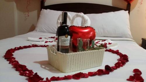 a basket with a bottle of wine and a heart on a bed at The Redwoods SM Fairview with Balcony in Manila