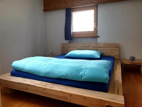 a bedroom with a wooden bed with a blue pillow at Ferienwohnung Hinteregger in Fuldera