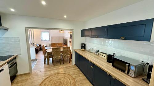 une cuisine avec des armoires bleues et une salle à manger dans l'établissement Les Oréades Le Mont Dore 10pers, à Le Mont-Dore