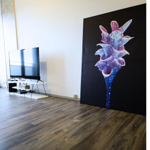 une peinture d'une fleur sur un mur à côté d'une télévision dans l'établissement Belle vue appart, à Saint-Louis