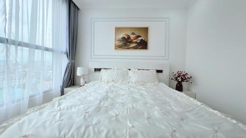 a white bedroom with a large bed and a window at KABILUX HOUSE - 1-2-3 Bedrooms in Vinhomes Times City in Hanoi