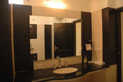 a bathroom with a sink and a large mirror at Hotel Vikramaditya in Gangānagar