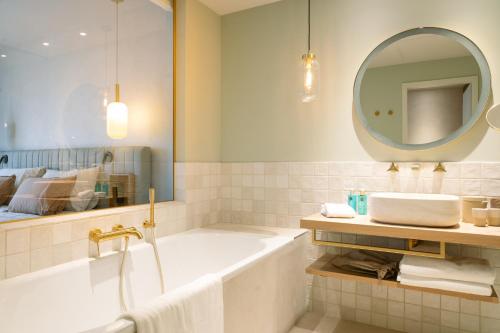 a bathroom with a tub and a mirror and a sink at A-ROSA Gardasee in Salò