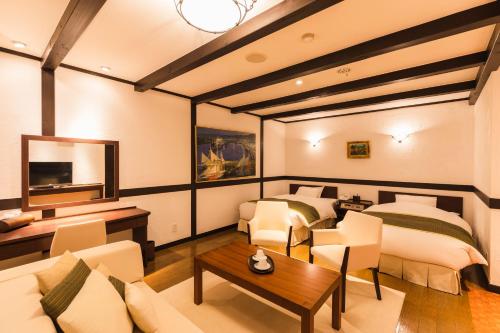 a room with two beds and a couch and a table at Hotel Jogakura in Aomori