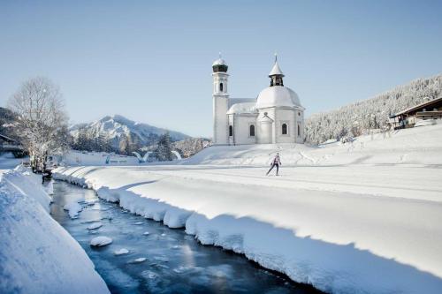 a person skiing on a snow covered river in front of a church at LakeSide Apartments Seefeld in Seefeld in Tirol