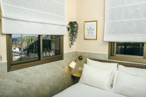 a bedroom with two windows and a bed with white pillows at Domus Bat Galim Hotel in Haifa