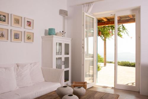 a living room with a white couch and a sliding glass door at Hacienda house in Andiparos