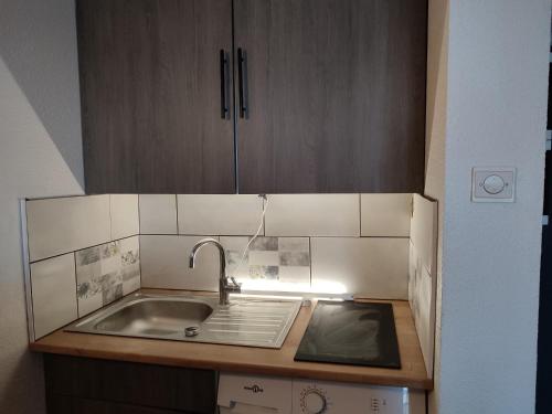 une cuisine avec un évier et des armoires en bois dans l'établissement Au mouillage, appartement 2 pièces plage de Pontaillac, à Vaux-sur-Mer