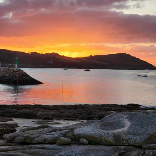 un coucher de soleil sur un plan d'eau avec des bateaux à l'intérieur dans l'établissement Soizic' house, à Trébeurden