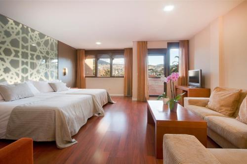 una camera d'albergo con due letti e un divano di Hotel Granada Palace a Monachil