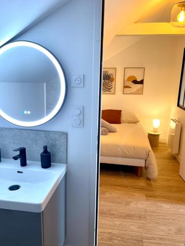 a bathroom with a sink and a bedroom with a bed at L'Ecluse - Appartement in Tinténiac