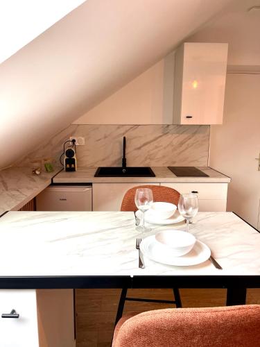 a kitchen with a table with two plates and wine glasses at L'Ecluse - Appartement in Tinténiac
