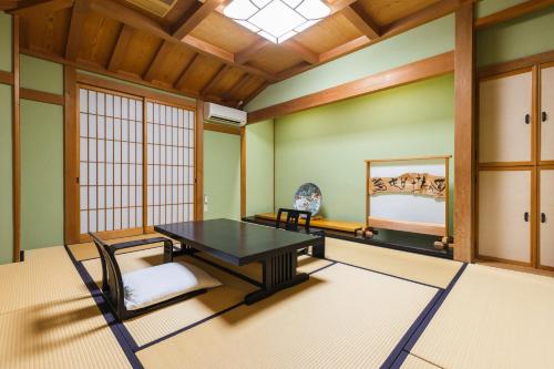 a room with a table and chairs and a window at Hotel Jogakura in Aomori