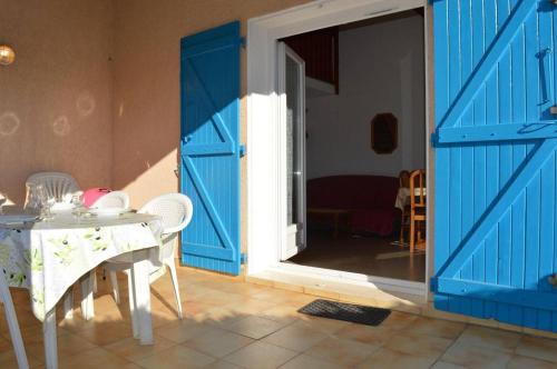 Cette chambre dispose d'une porte bleue ainsi que d'une table et de chaises blanches. dans l'établissement Maison 2 pièces mezzanine 6 couchages SAINT CYPRIEN SC880-020, à Saint Cyprien Plage