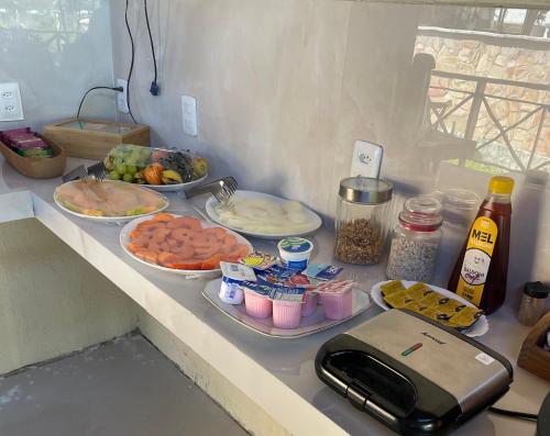 a counter with plates of food and bowls of food at Pousada Monteflor Guaramiranga-CE in Guaramiranga