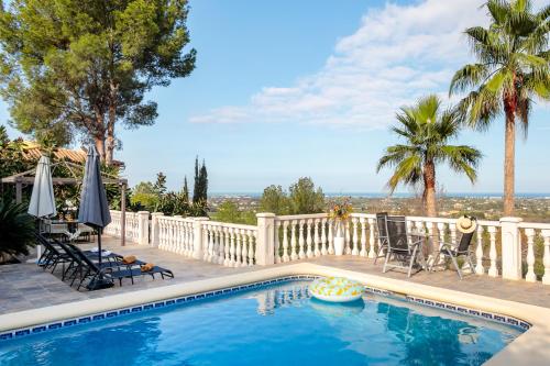 a swimming pool with chairs and umbrellas on a patio at Villa Amarilis in Casas Albardanera
