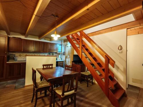 a kitchen and dining room with a wooden table and stairs at Val di Sole Family Apartments in Malè