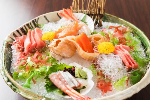 a bowl of food with sushi and vegetables on a table at Hotel Jogakura in Aomori