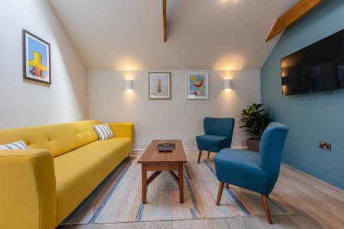 a living room with a yellow couch and two blue chairs at Waterside Apartment in Paignton
