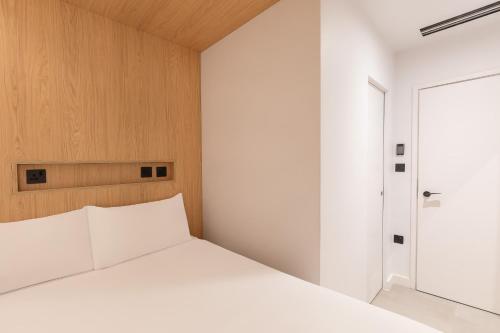 a bedroom with a white bed and a door at Zedwell Hotel Knightsbridge in London