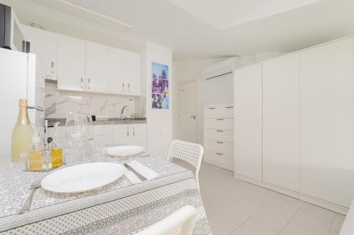a white kitchen with a table and white cabinets at Buhardilla con terraza acogedora in Coslada