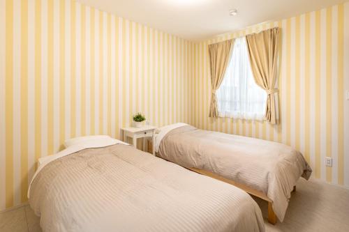 前橋市にあるGUMPAKU Maebashi - Vacation STAY 81491vのストライプ壁の客室内のベッド2台