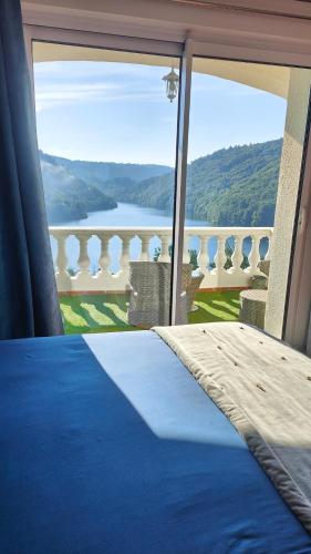 a bedroom with a bed and a view of a balcony at Ma villa au bord de l'eau in Miremont