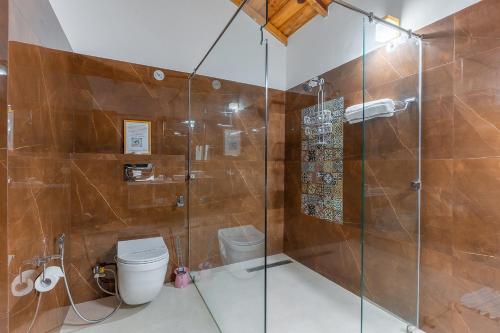 a bathroom with a glass shower with a toilet at Vibhasa-The Scenic Solitude Villa Amidst Himalayas Near Kainchi Dham-Where BBQ and Bonfires Ignite the Adventure in Rāmgarh