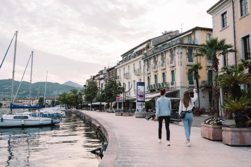 a man and woman walking down a street next to a canal at A-ROSA Gardasee in Salò