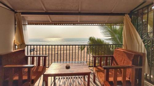 a balcony with a table and chairs and a view of the ocean at Madhu Huts Agonda in Agonda