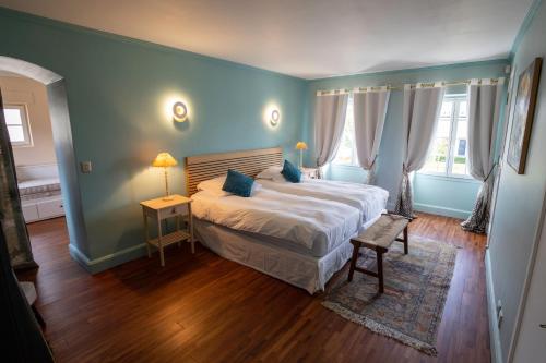 - une chambre avec un grand lit, des murs bleus et du parquet dans l'établissement Domaine Chapelle, à La Chapelle-la-Reine