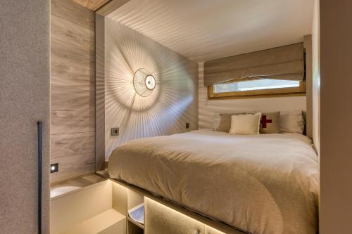 une chambre avec un lit et une horloge au mur dans l'établissement Résidence Le Floréal - Megève, à Megève