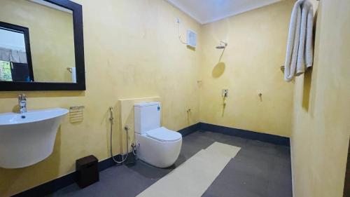 a bathroom with a white toilet and a sink at Ela Addara Green Villa in Sigiriya