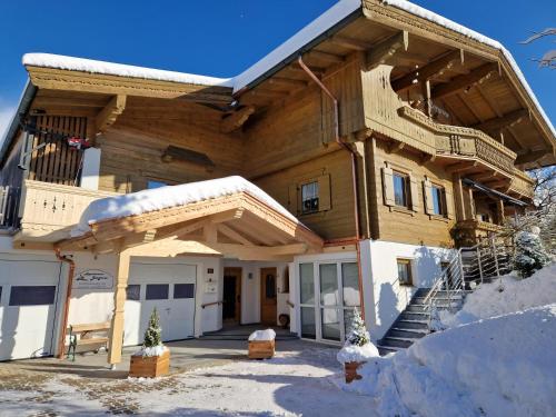 a wooden house with a porch and stairs in the snow at Appartement Bergrose in Hopfgarten im Brixental