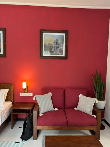 a red living room with a red couch and a bed at Leel’s Safari Cottage in Udawalawe