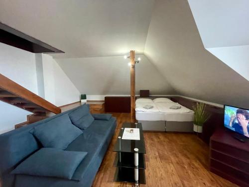 a living room with a blue couch and a bed at Hotel Aldo in Uničov